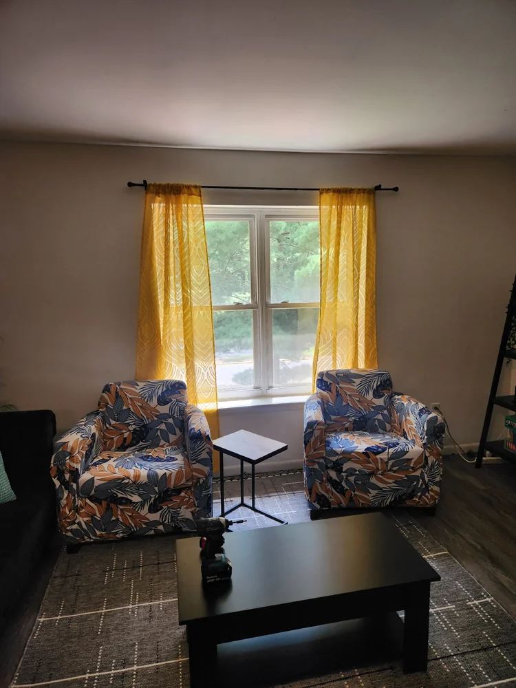 Yellow curtains hung on a black rod above a living room window