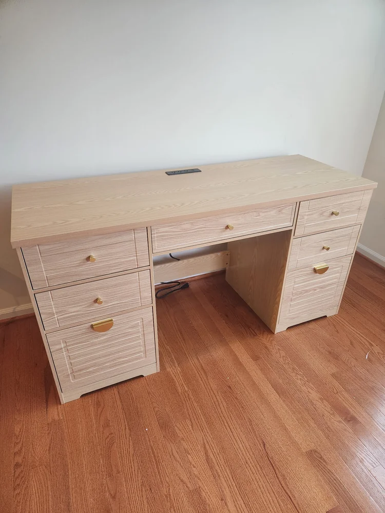 Assembled wooden desk with drawers and a built-in power strip
