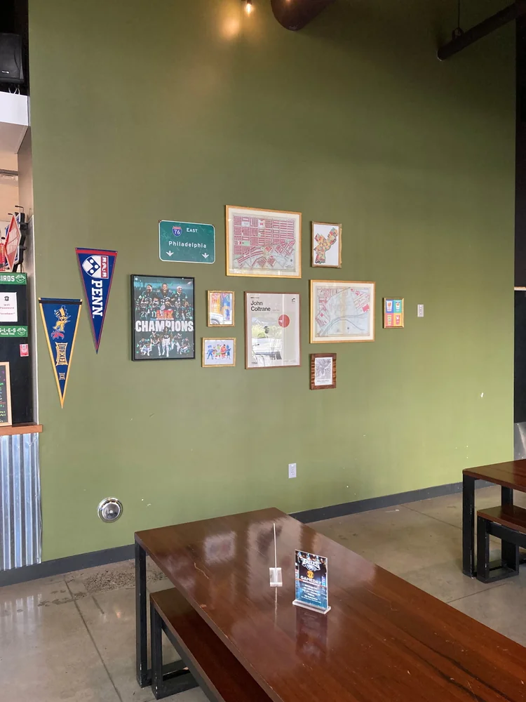 Framed Philadelphia artwork and pennants arranged on a green wall